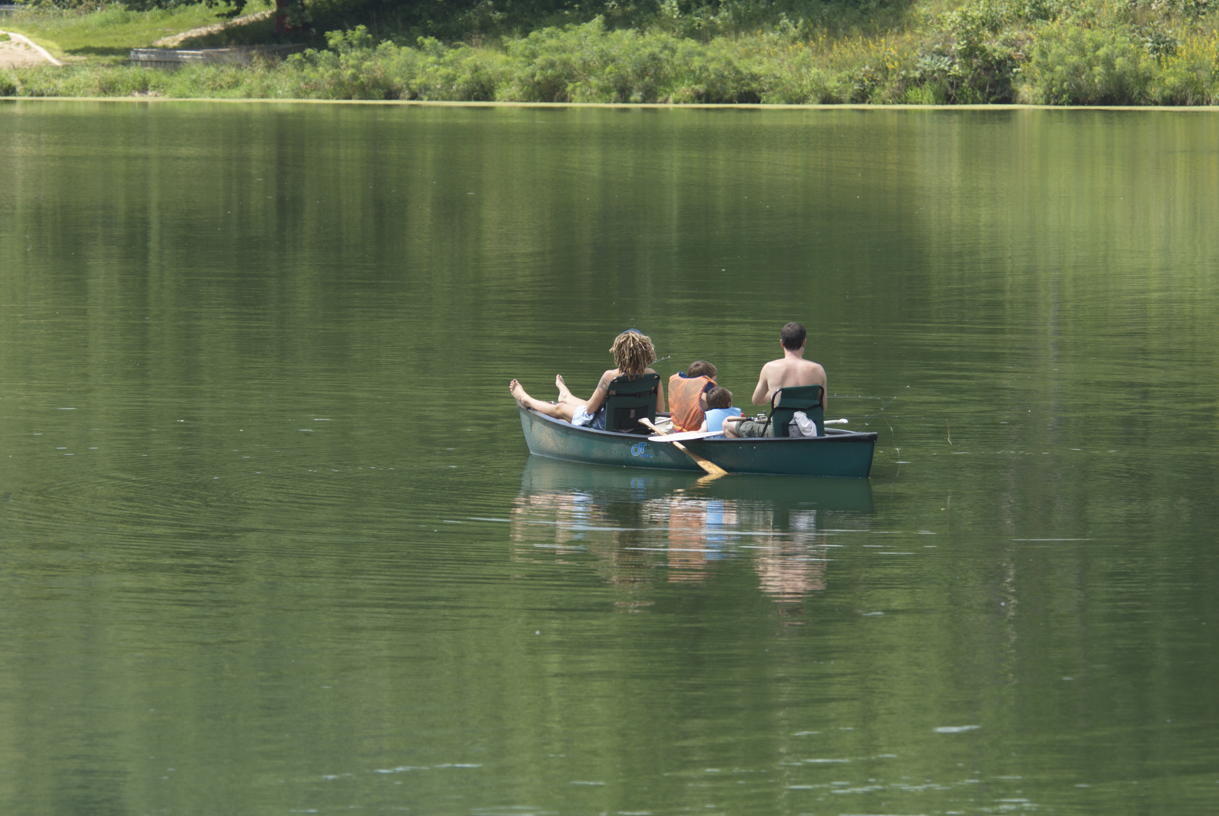 people fishing on a small boat in the middle of a body of water