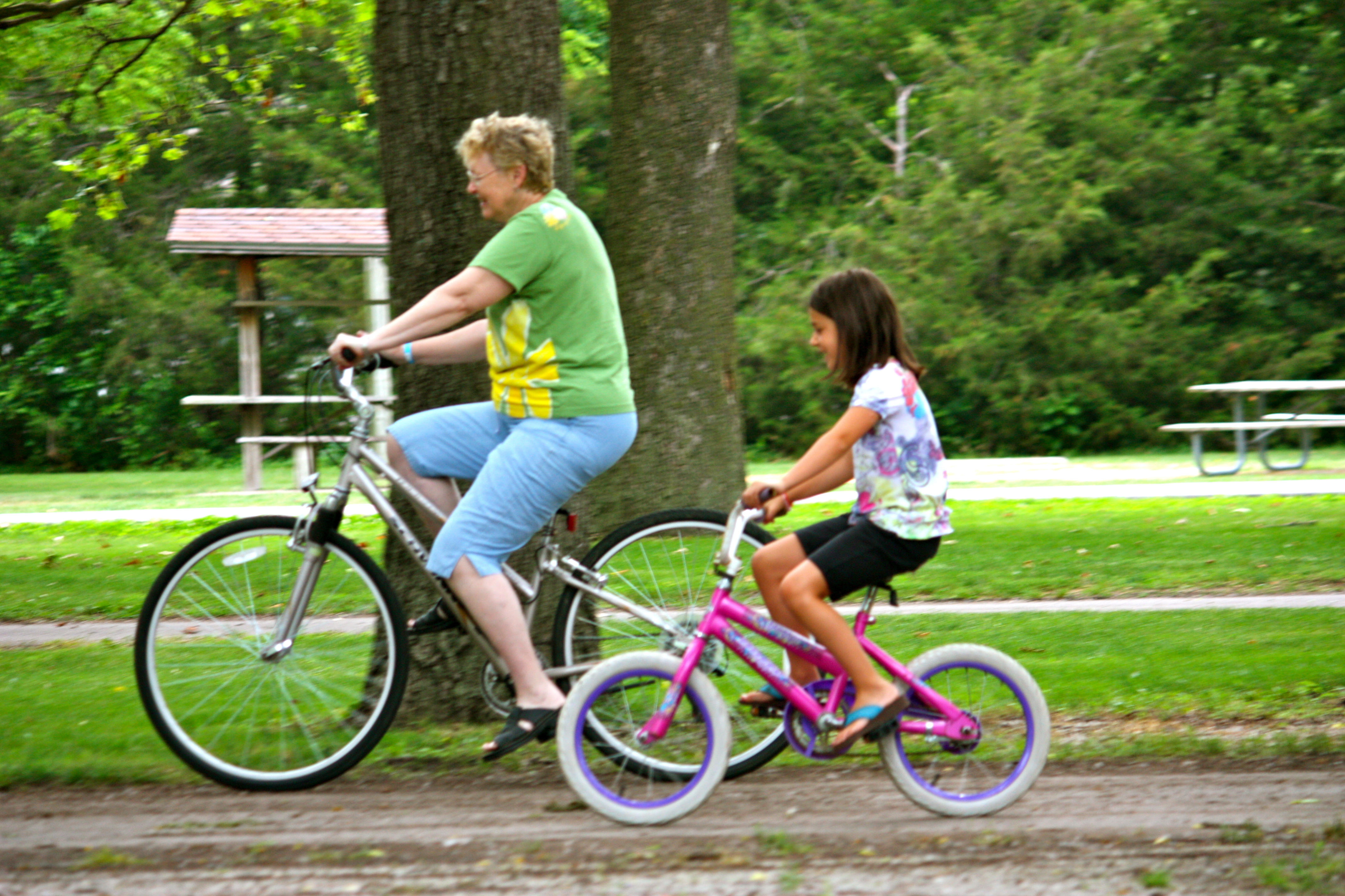 an adult and child riding on bikes together on a path