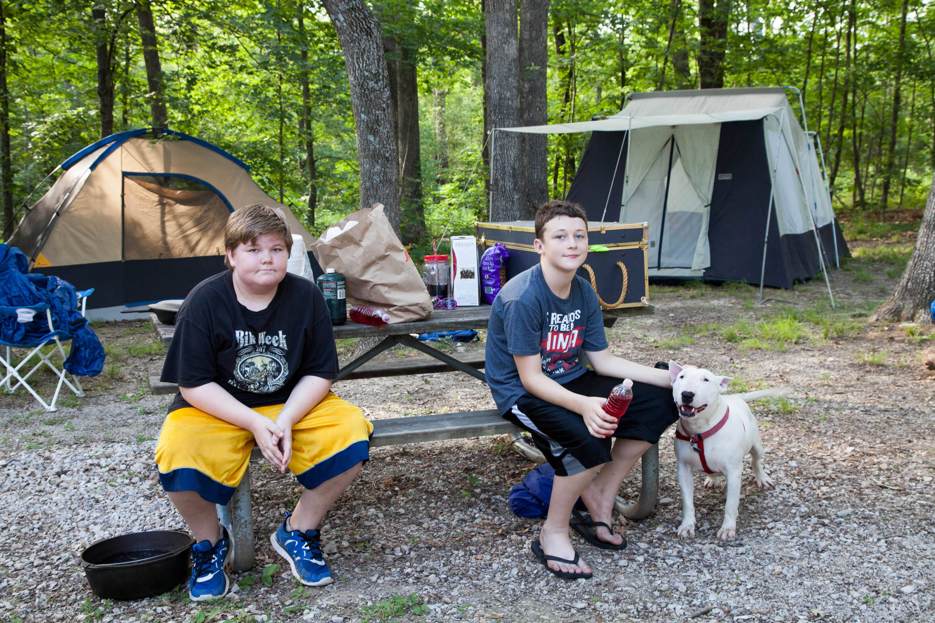 Two kids sitting at a picnic table in a camp grounds