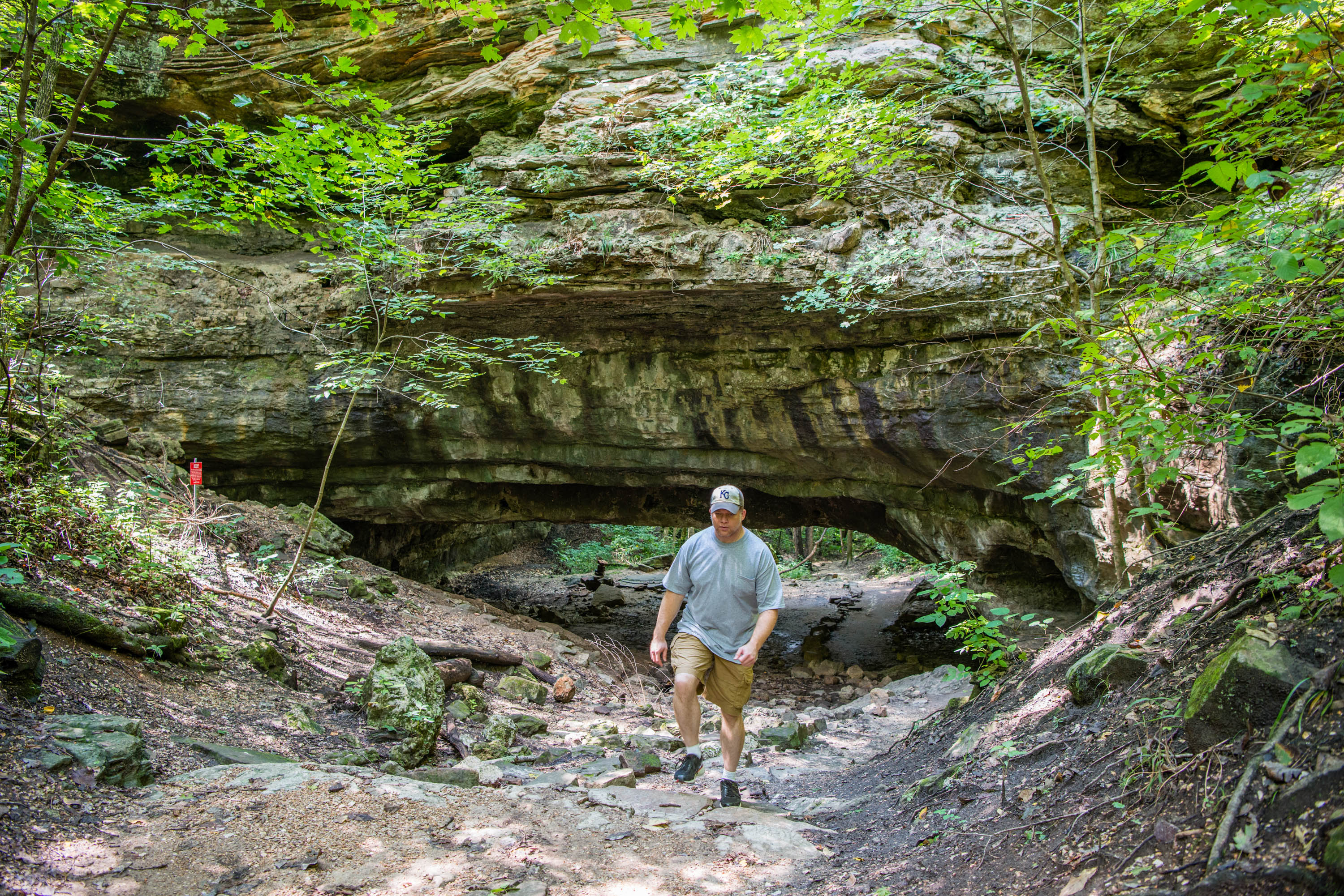 A man hiking in front of a rocky overpass