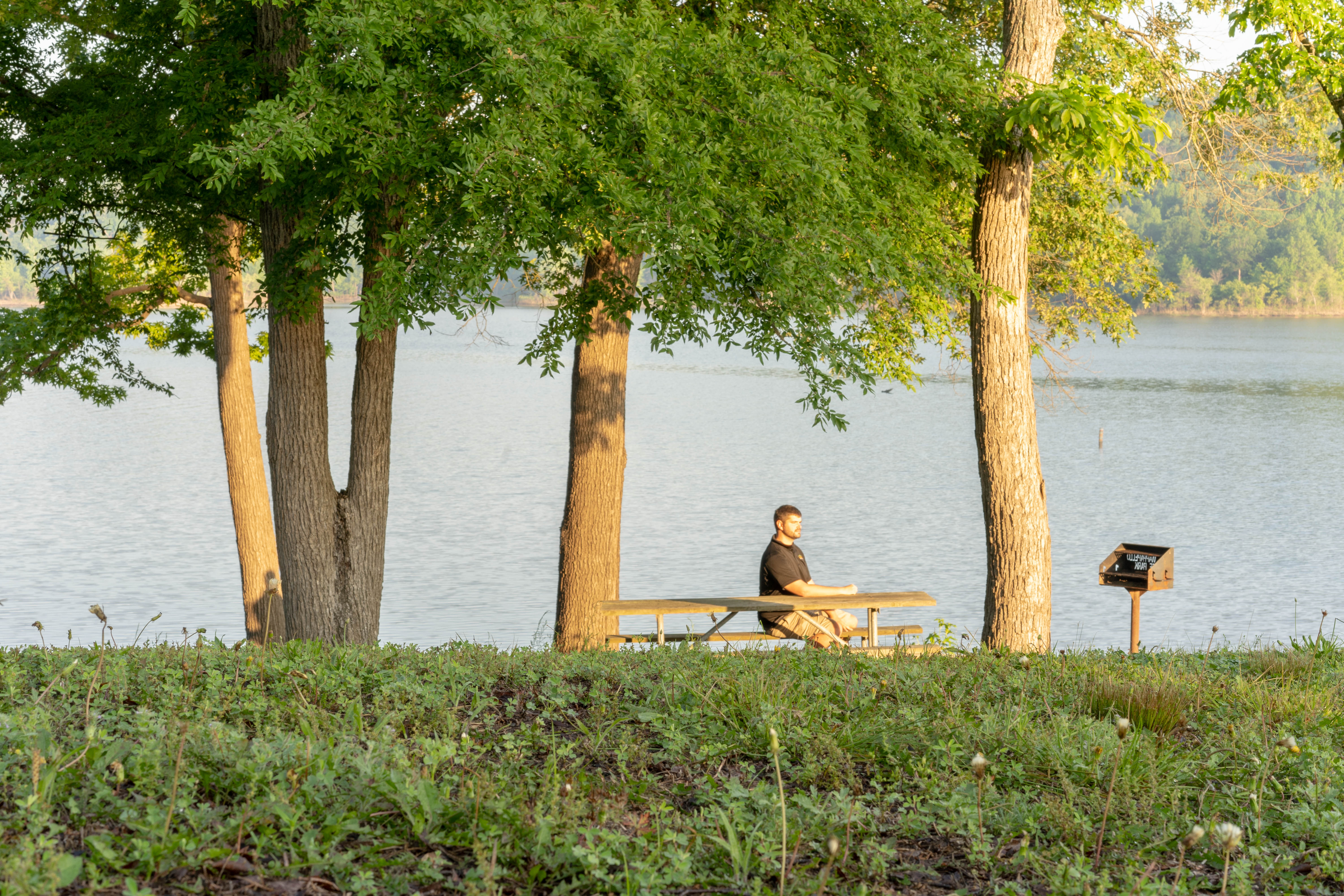 A person sitting at a picnic table by the water