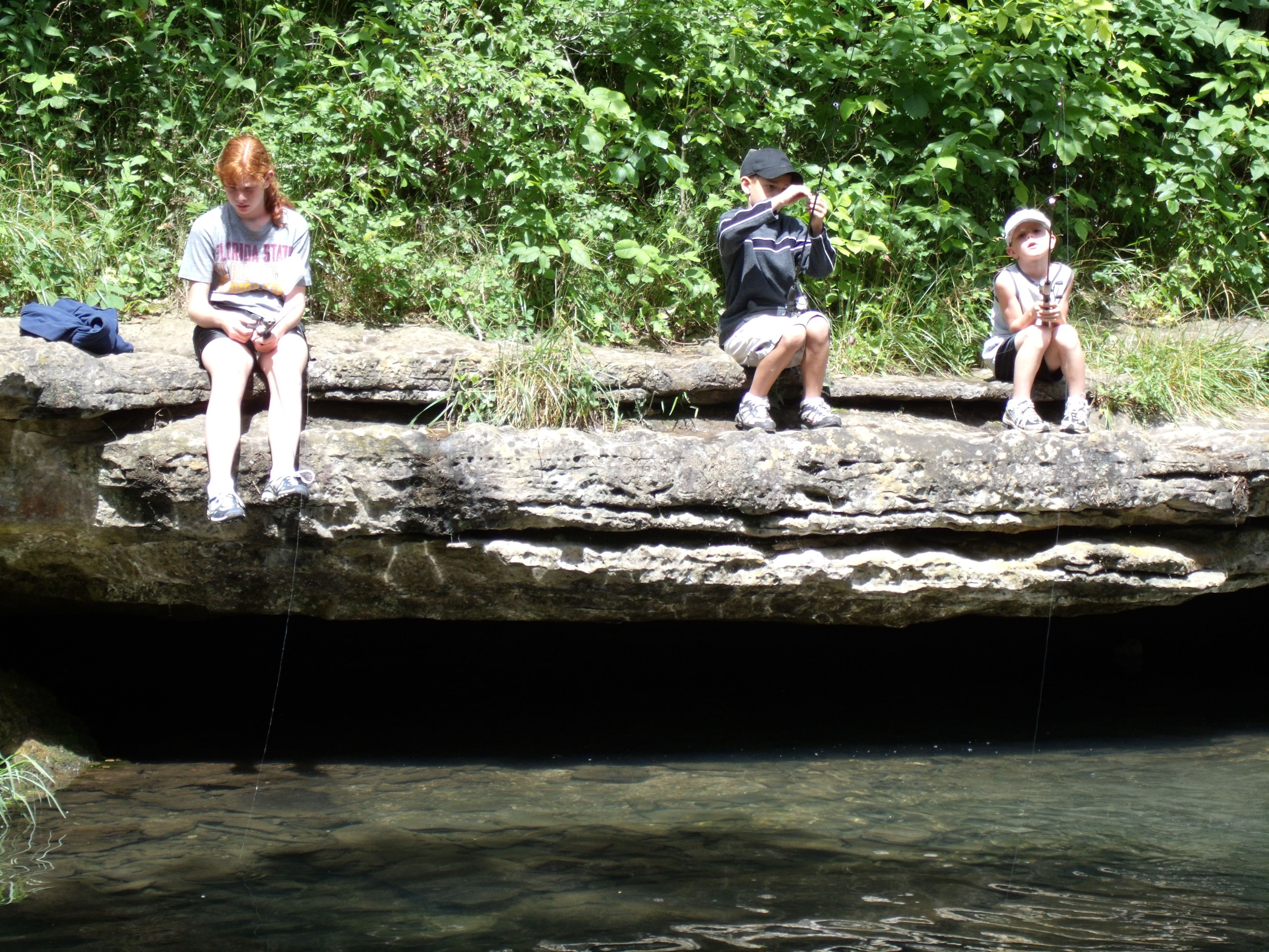 3 people sitting on a tree trunk by the river at Roaring River State Park