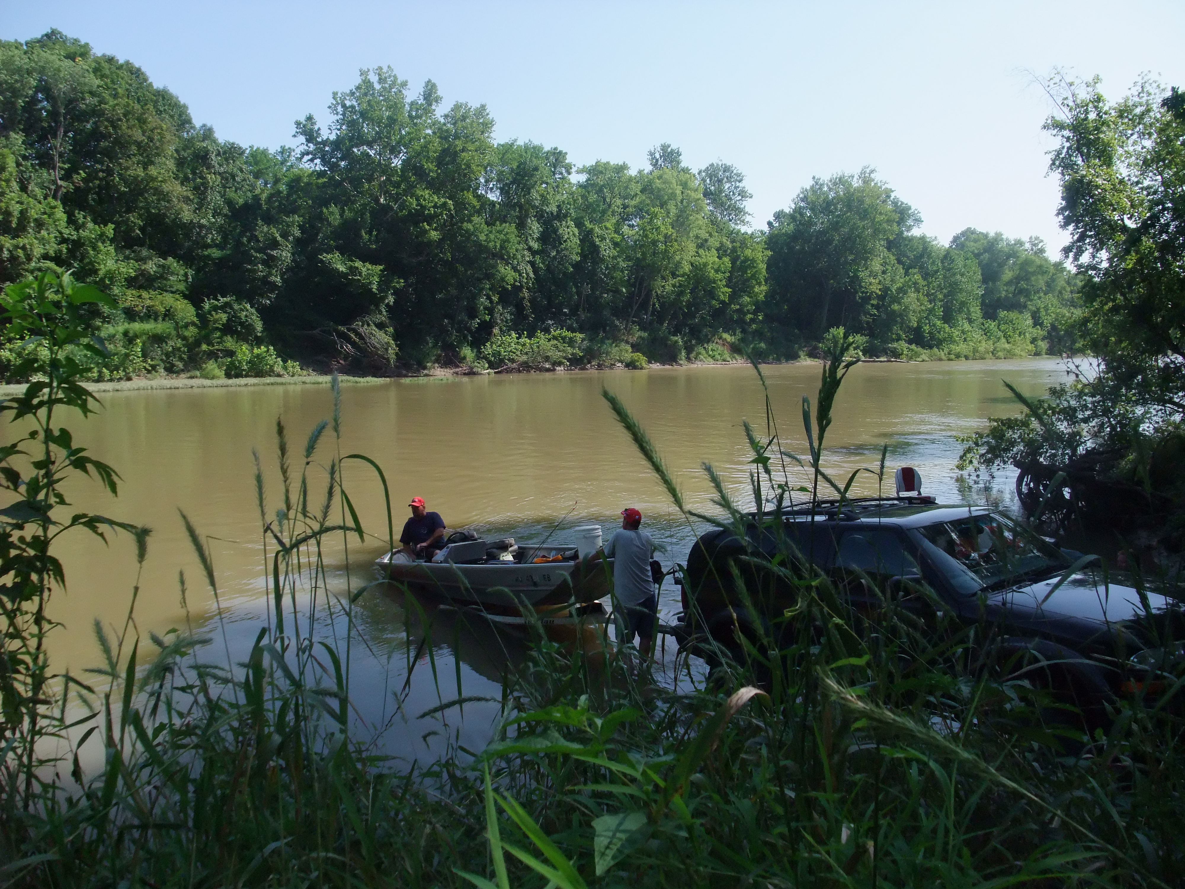 people backing a boat into a river