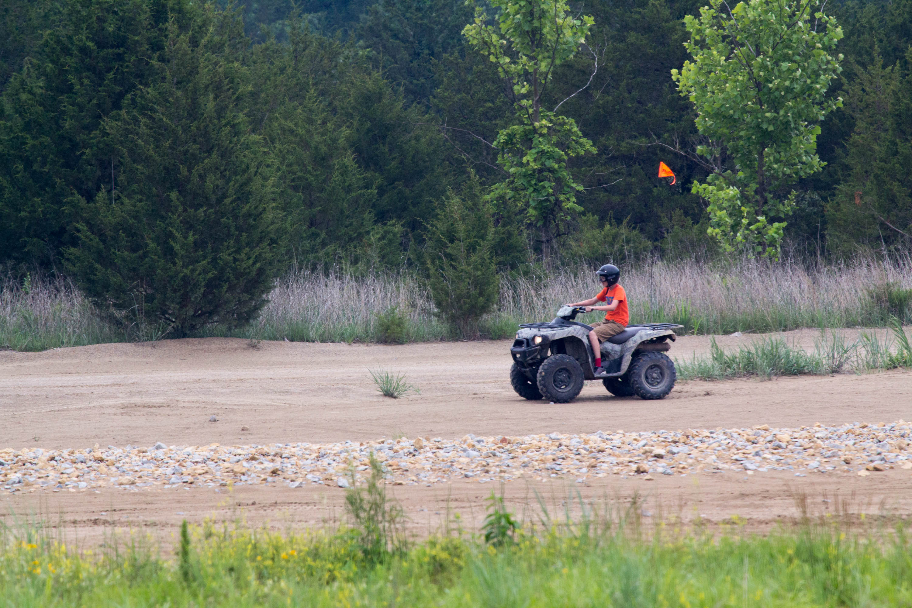 A kid riding a four wheeler in a dirt clearing