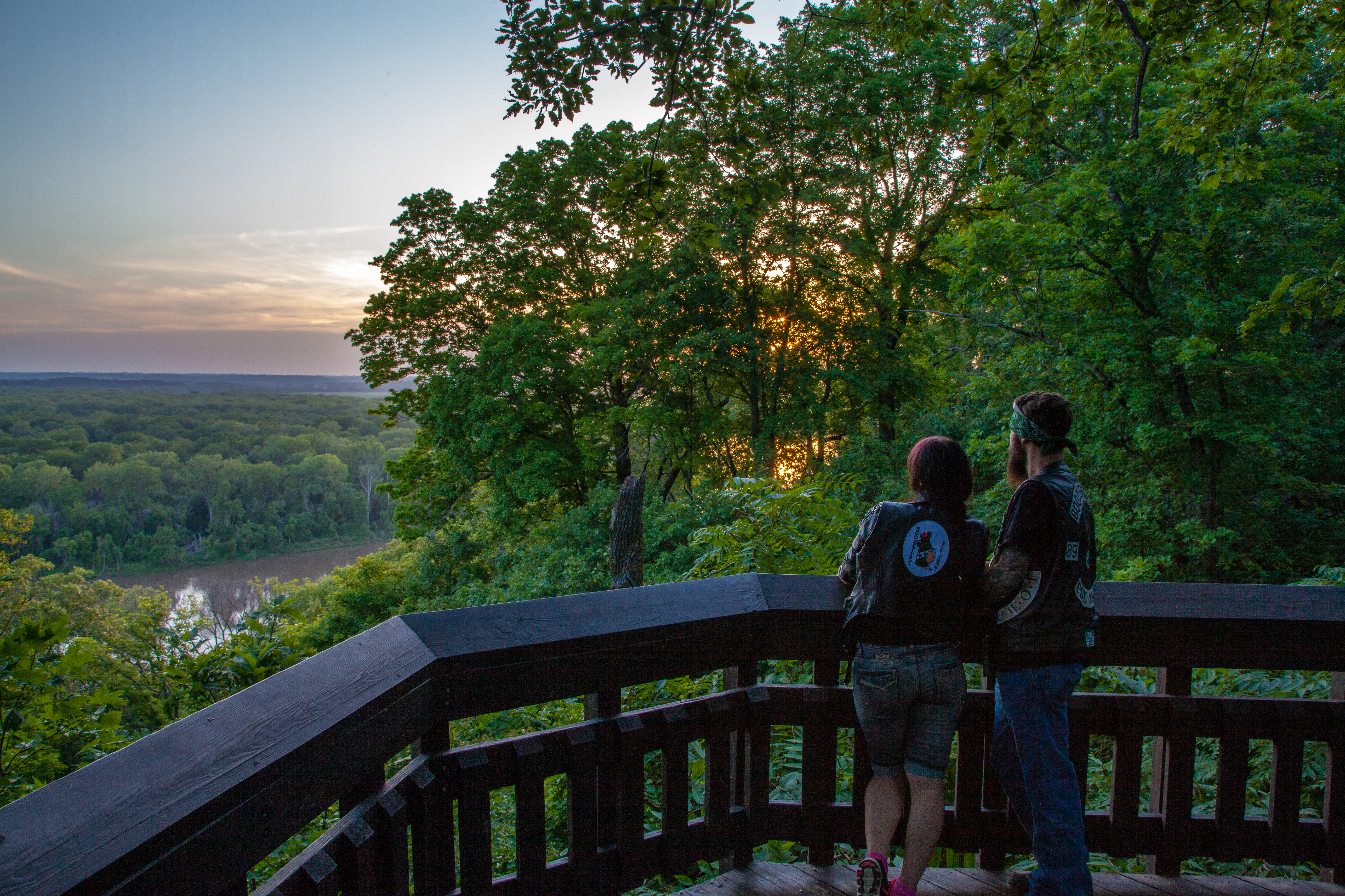 Two people on a balcony overlooking the woods