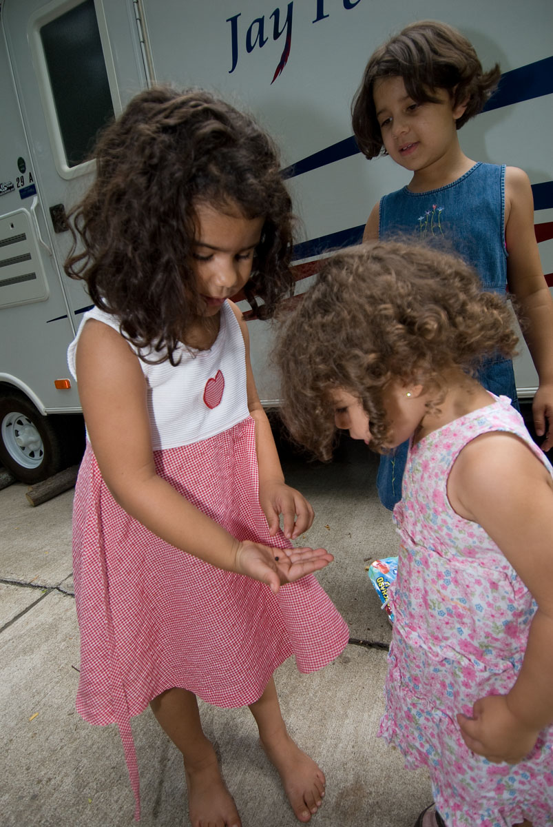 A child showing two other children a roly-poly