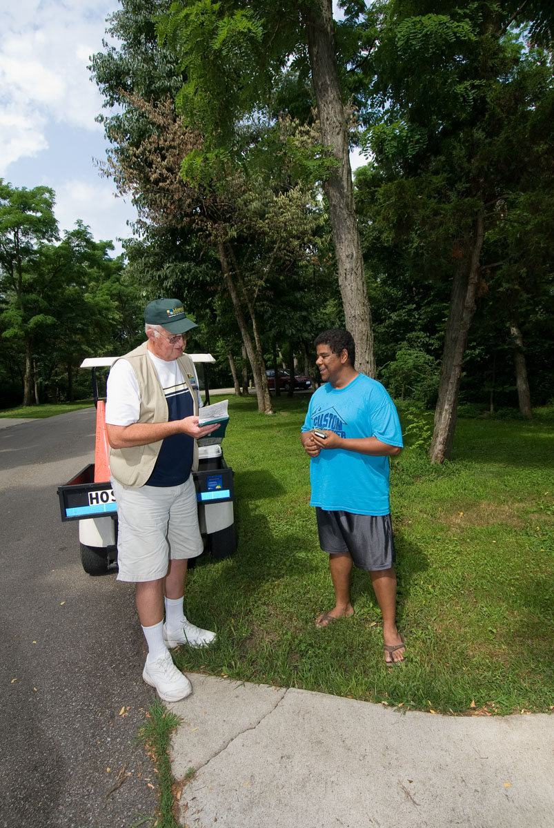 Two men talking at a campsite next to a golf cart