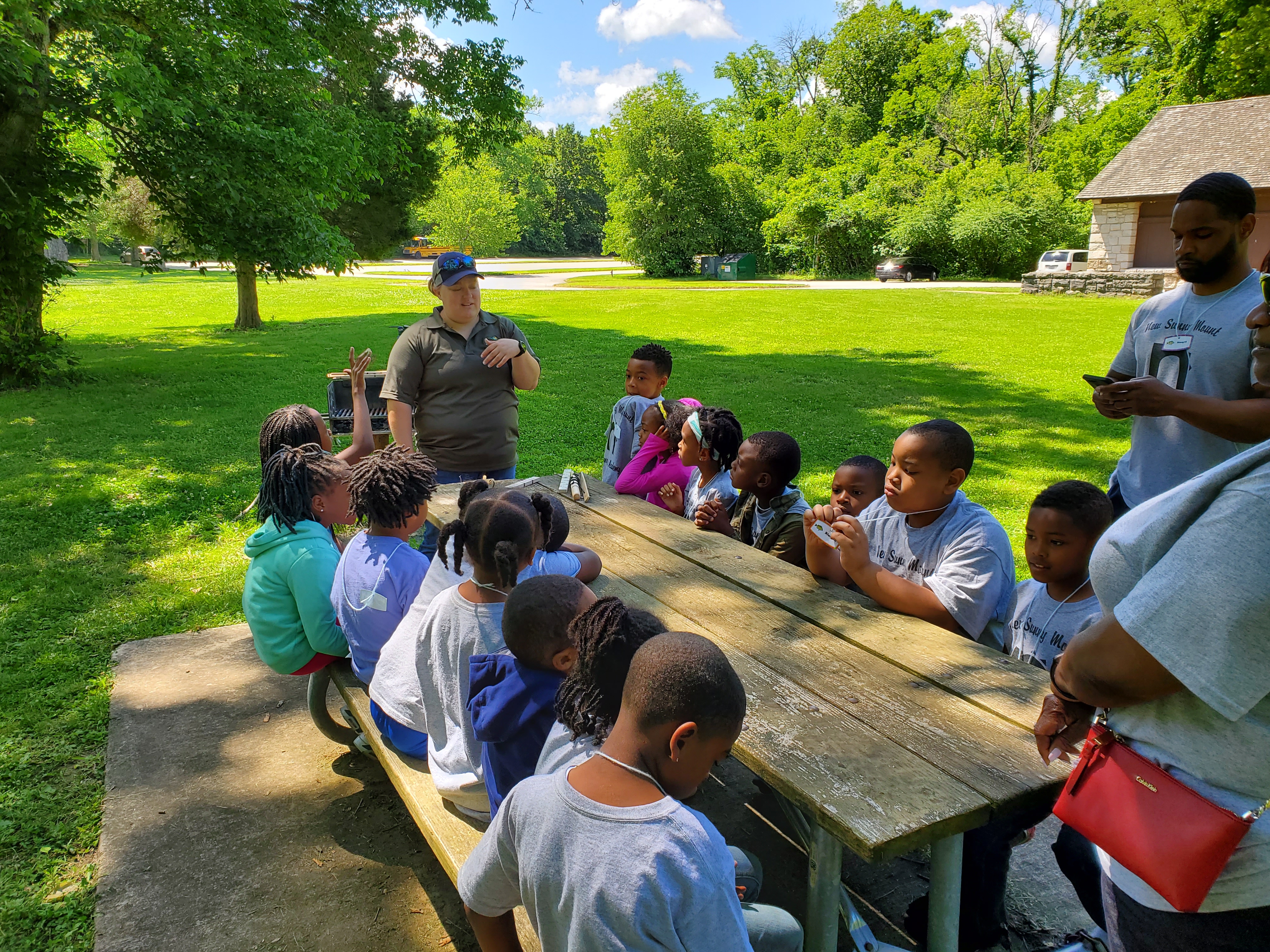 A group of kids being taught at a picnic table