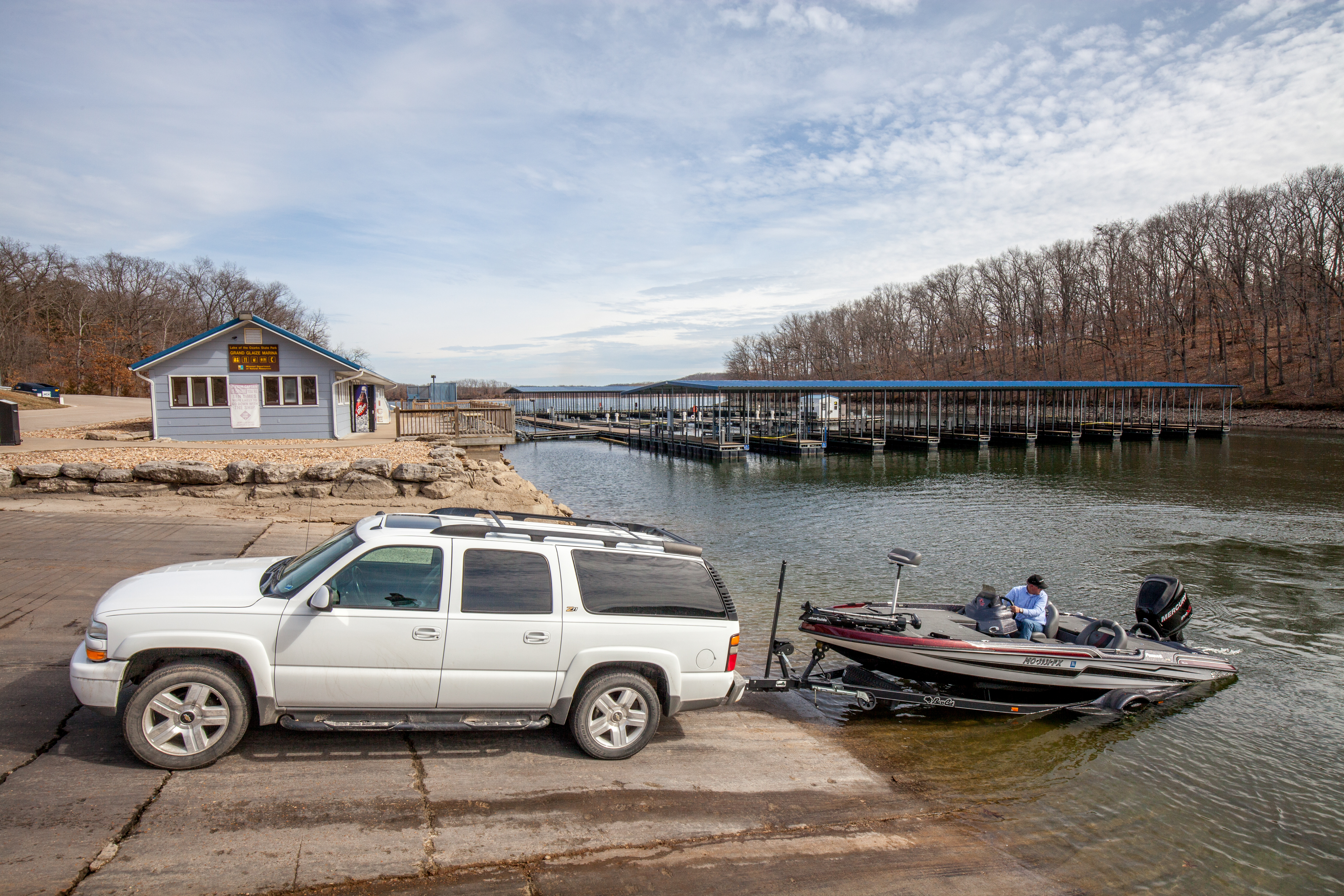 A boat being lowered into a lake by a car on a ramp