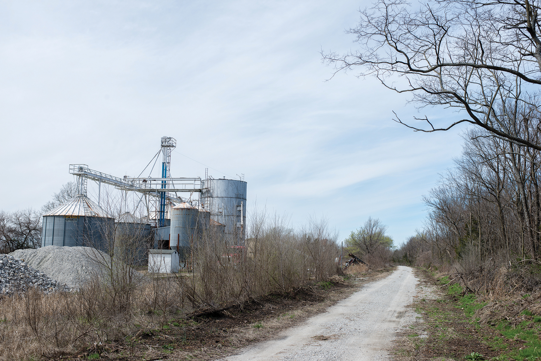 A dirt road with metal silos next to it