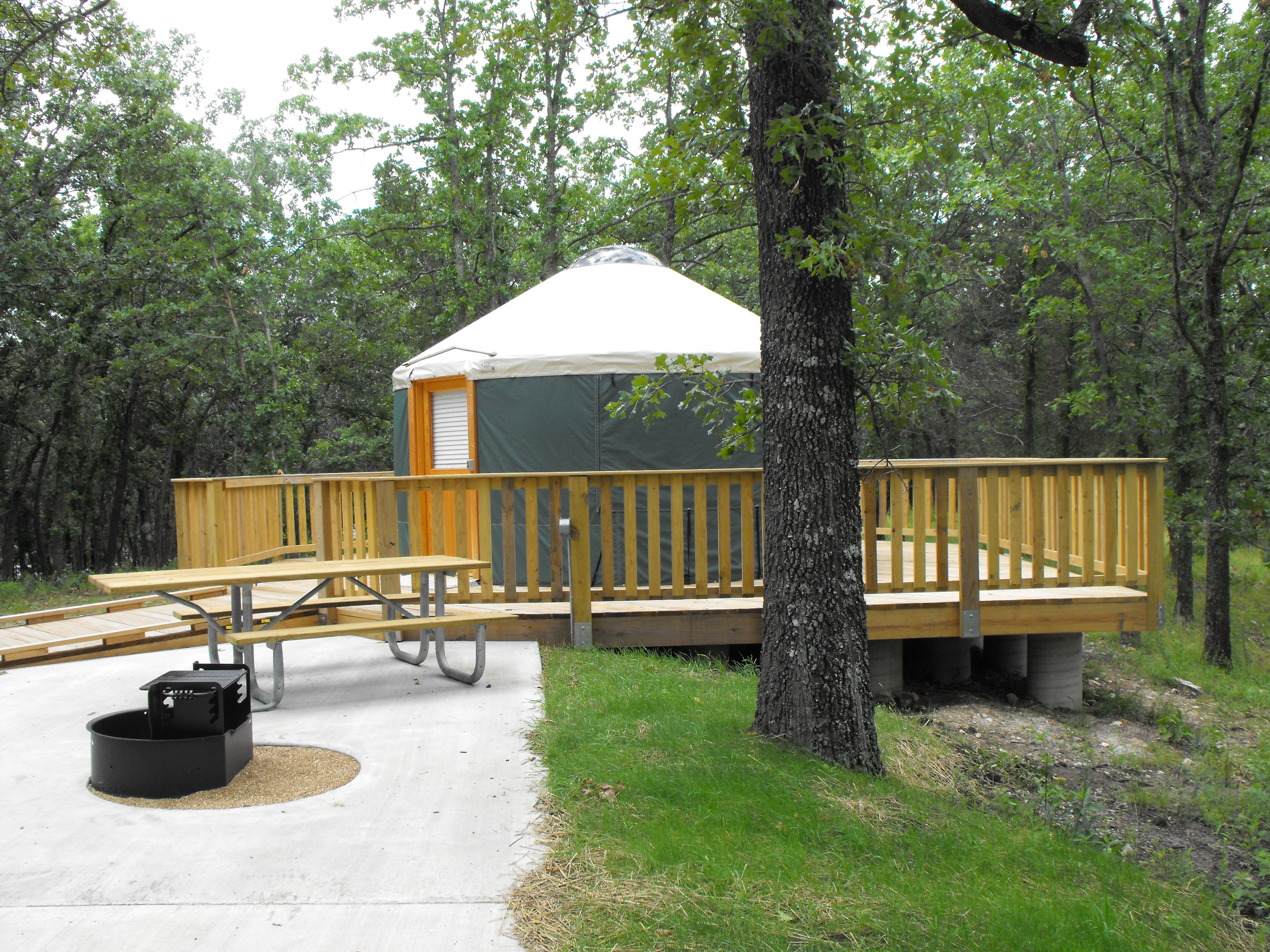 A tent on a wooden deck with a fire pit nearby