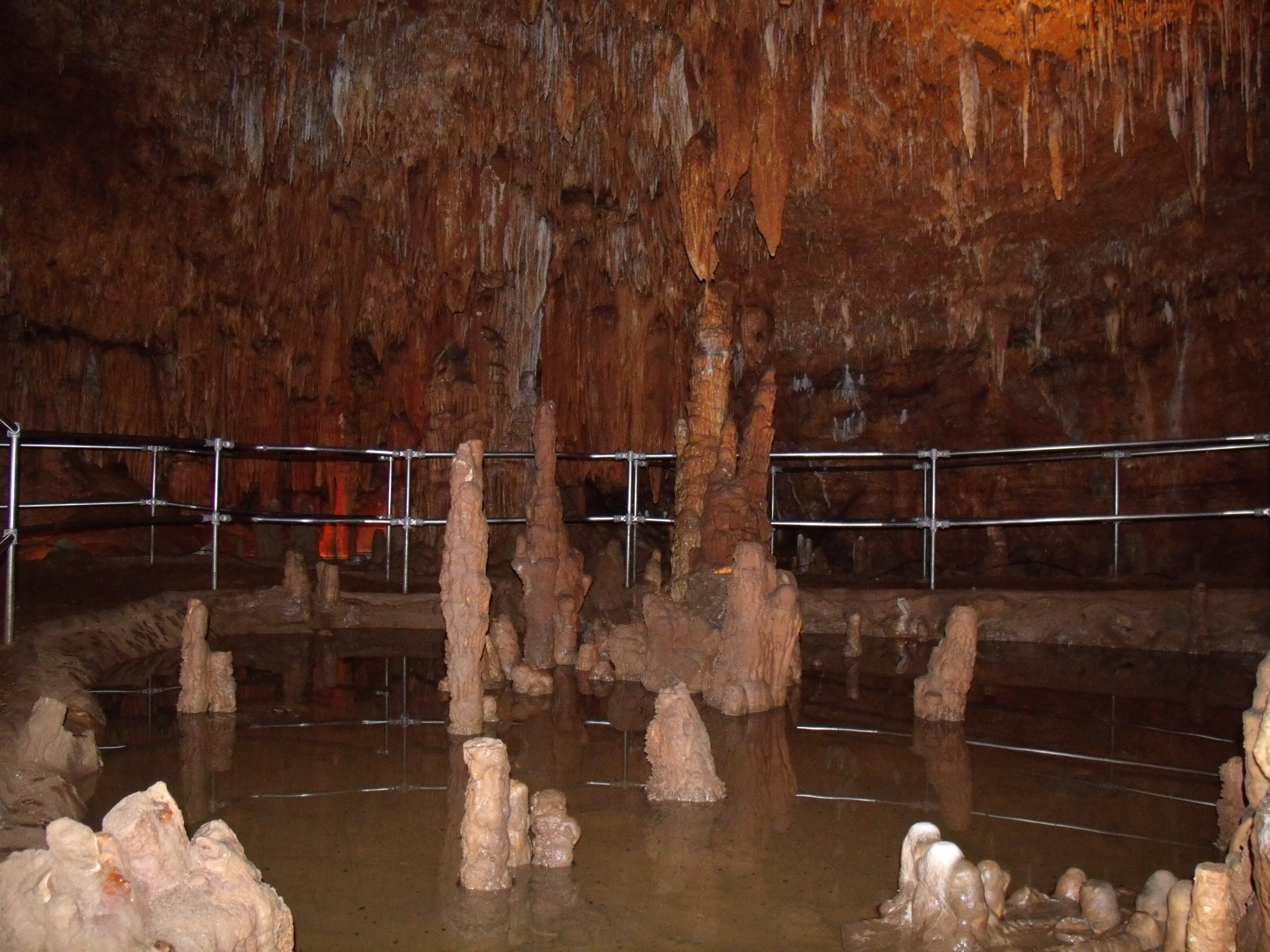A fenced in path along a pool of water in a cave