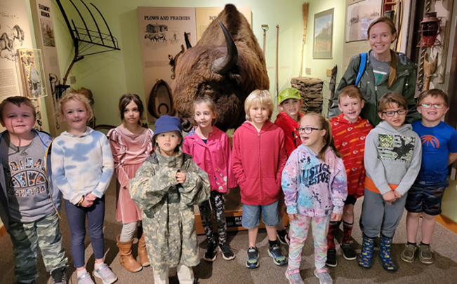 Kids gathered in front of a bison statue