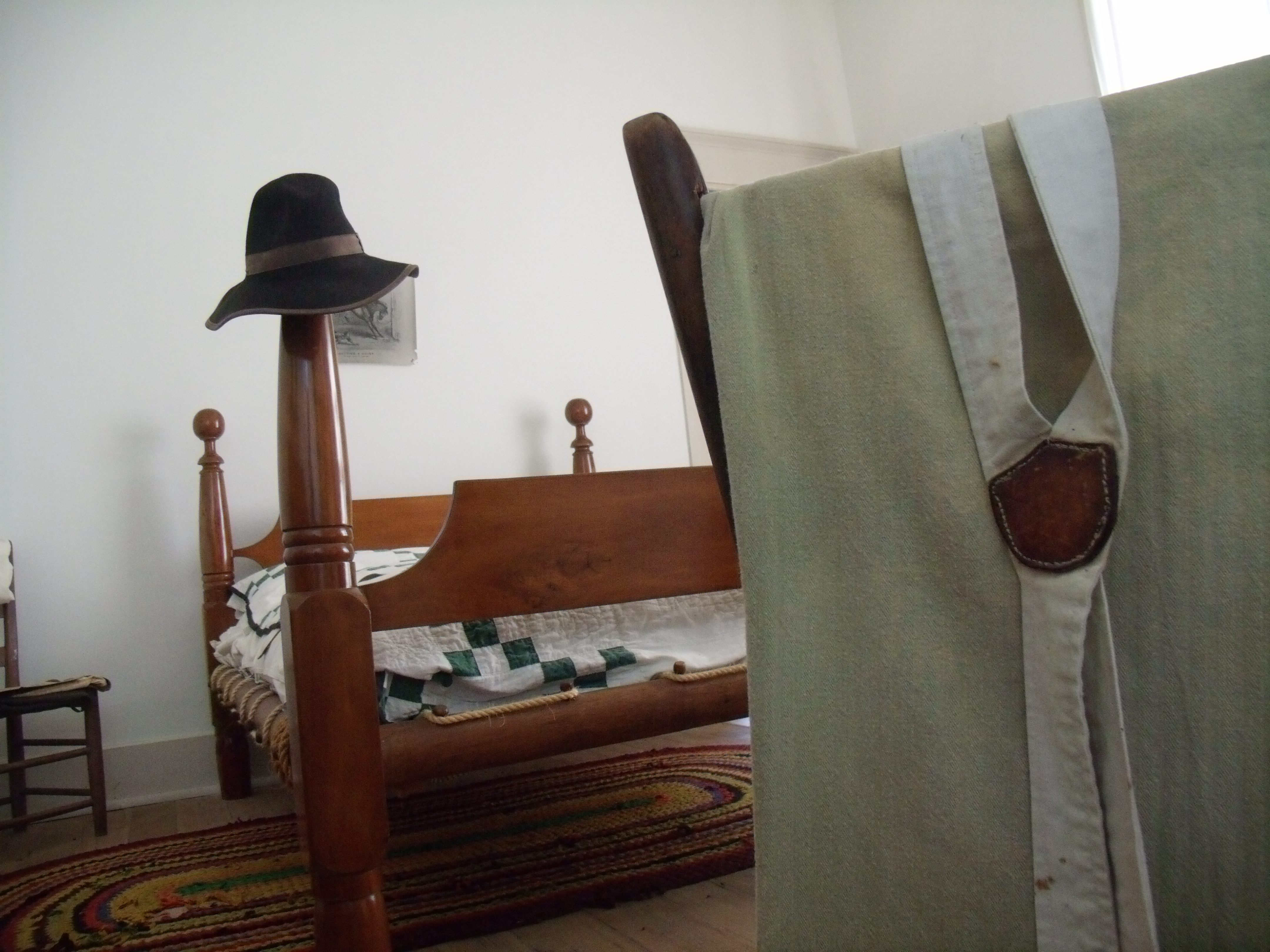 A wooden bed, a hat on the foot rest