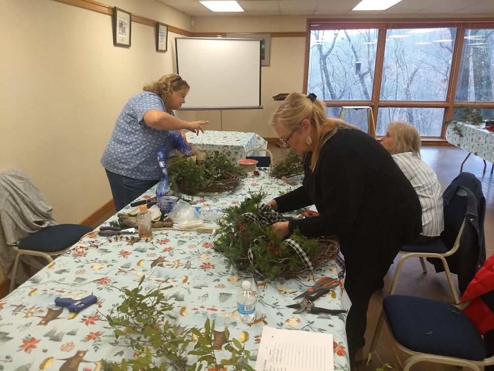 Three people making wreaths in a rec room