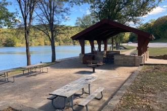 Picnic tables, grill and open shelter next to the lake
