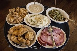 Fried chicken, mashed potatoes, ham, green beans and gravy on a serving tray