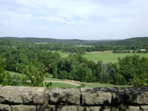 A stone wall overlooking wooded green hills