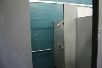 shower stall with blue tile and a handrail
