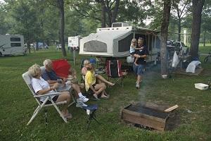 tent , a cooler and lawn chairs set up next to a picnic table on a campsite