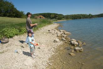 a man and boy fishing from the lake shore