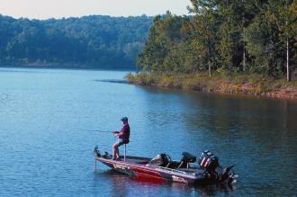 A man fishing out of his boat on a lake.