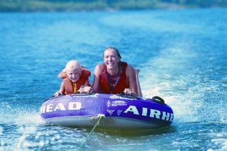 A mother and young daugher tubing on a lake.
