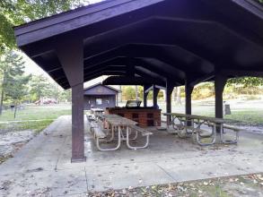 Open picnic shelter with restrooms and playground in background