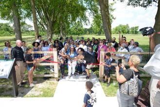A large group of people at the ribbon cutting ceremony to celebrate the opening of the historic site