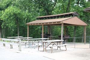open shelter with large grills and tables next to the enclosed shelter