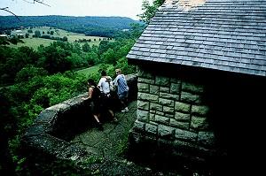 three people standing on an overlook next to a rock shelter enjoying a view of the valley