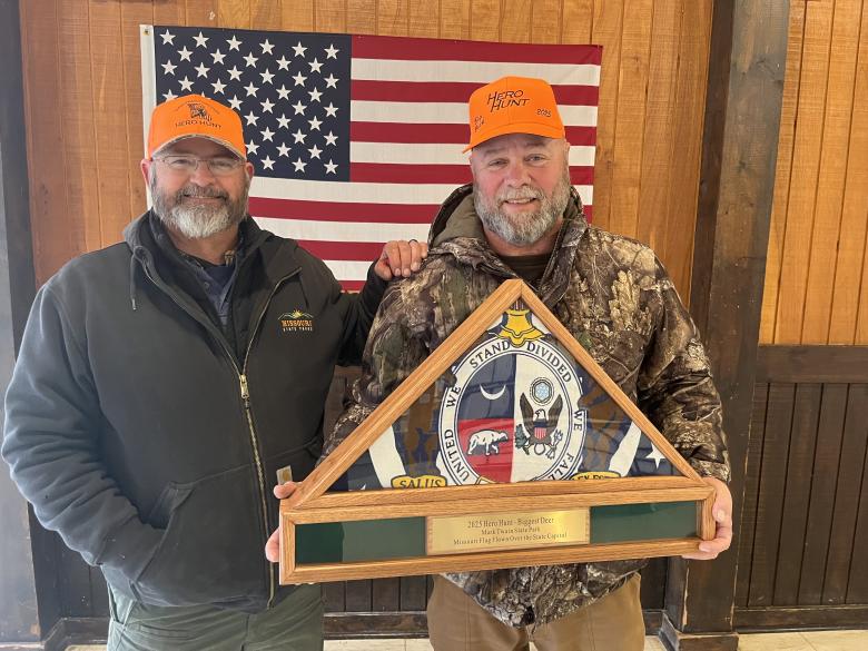 Two men standing with one of them holding the 2025 Hero Hunt Biggest Deer Award
