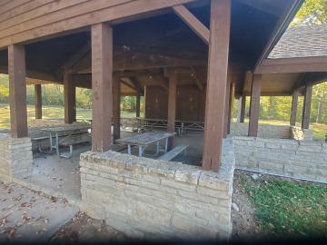 Picnic tables inside the wood-framed open shelter