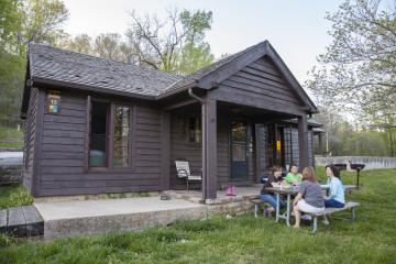 Cabin with wooden siding with picnic table out front.