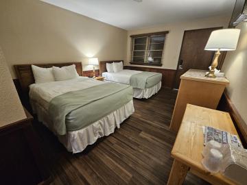 Room with two queen size beds, tables and lamps.