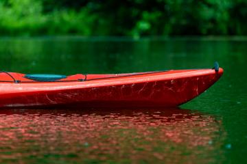 A closeup image of an orange kayak and its reflection on the water
