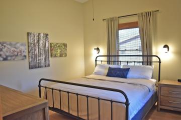 View of bedroom with bed, dresser and side table.