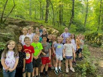 Students pose for a photo in the woods with green foliage in the background