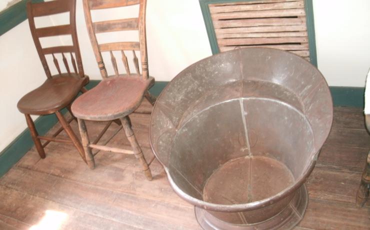 A bronze tub with two wooden chairs next to it