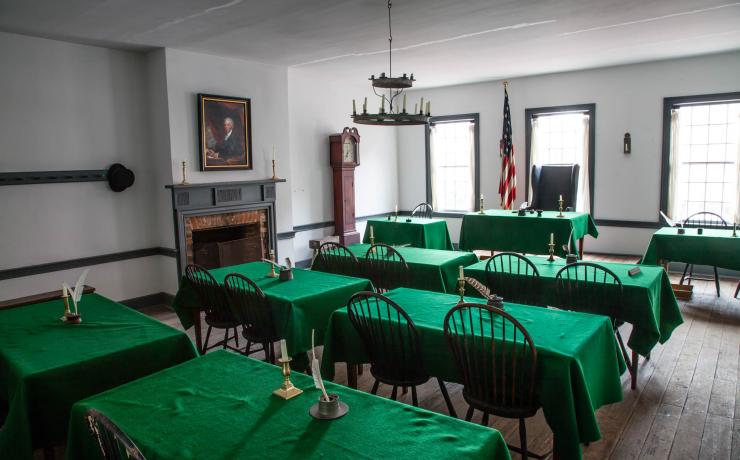 A meeting room with several tables covered by green table cloths