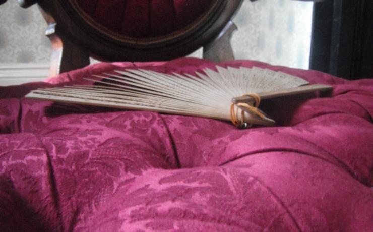 A folding fan sitting on a purple cushion