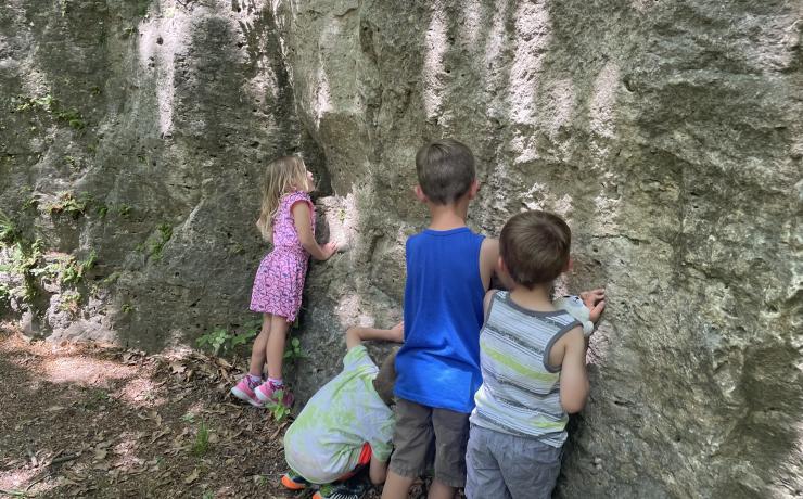 A group of four children explores a rocky outcrop