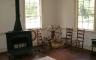 A colonial era living room with a wood burning stove and a spinning wheel
