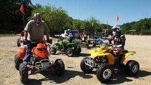 Three people on four wheelers, red, green, and yellow