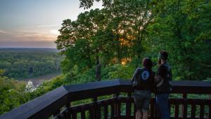 Two people on a balcony overlooking the woods