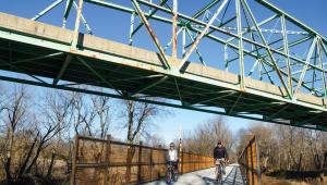 Two people biking under a bridge
