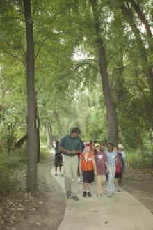 A park naturalist taking a group of schoolkids on a hike