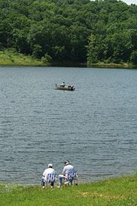 Two people fishing on the shore of a river