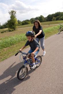 woman helping a child learn to ride a bike