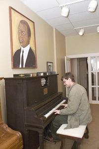 a man playing the piano inside the Joplin house